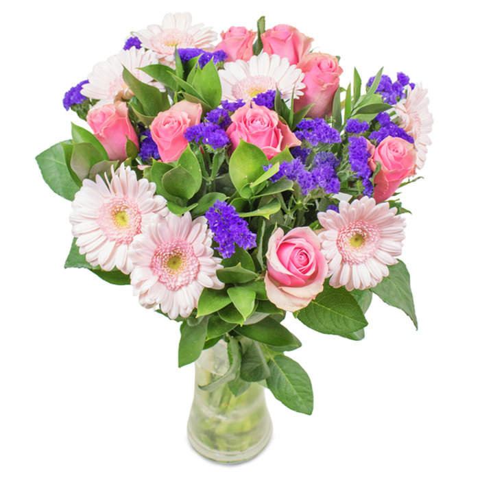Set in a sleek clear glass vase, this elegantly crafted bouquet celebrates the vibrancy and kindness that define Wealdstone. Taking centre stage, about seven to nine soft-to-medium pink roses display classic spiral forms-some still tightly furled, others just opening, their colours echoing local cherry blossoms in spring. Framing them are five to seven pale pink Gerbera daisies, each one marked by broad, round petals and lighter, nearly white centres-mirroring the delicate balance found in the flowerbeds of Chandos Recreation Ground. Interspersed clusters of vivid purple statice introduce vibrant texture and a deeper tone, balancing the arrangement's blush hues. Surrounding all, lush green foliage adds refreshing depth and a woodland fragrance, reminiscent of walks along Headstone Road. Stems and sparkling water are visible through the glass, enhancing a sense of natural freshness and recent gathering. An apt choice for birthdays, anniversaries, Mother's Day, or as a charming gift for any Wealdstone home or office, this bouquet of hand-chosen pink roses, Gerberas, and purple fillers expresses celebration and heartfelt joy.